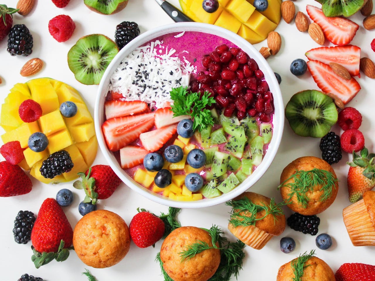who-we-are Vibrant smoothie bowl topped with assorted fresh fruits and muffins, perfect for a healthy snack.