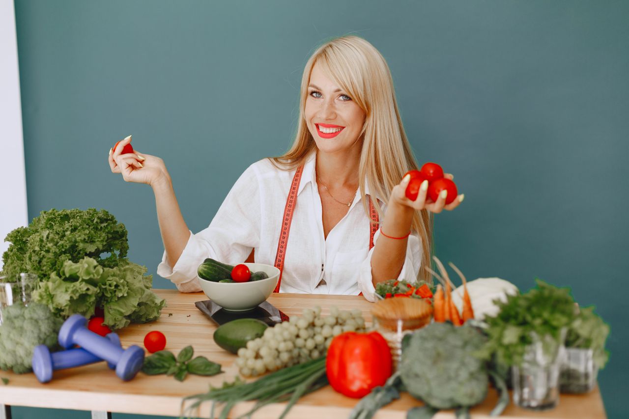 services-01 Healthy lifestyle concept with woman holding tomatoes and surrounded by fresh vegetables in a studio setting.